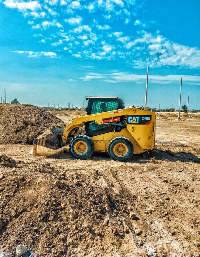 Home Skid steer loader at a daytime construction site with blue sky backdrop.